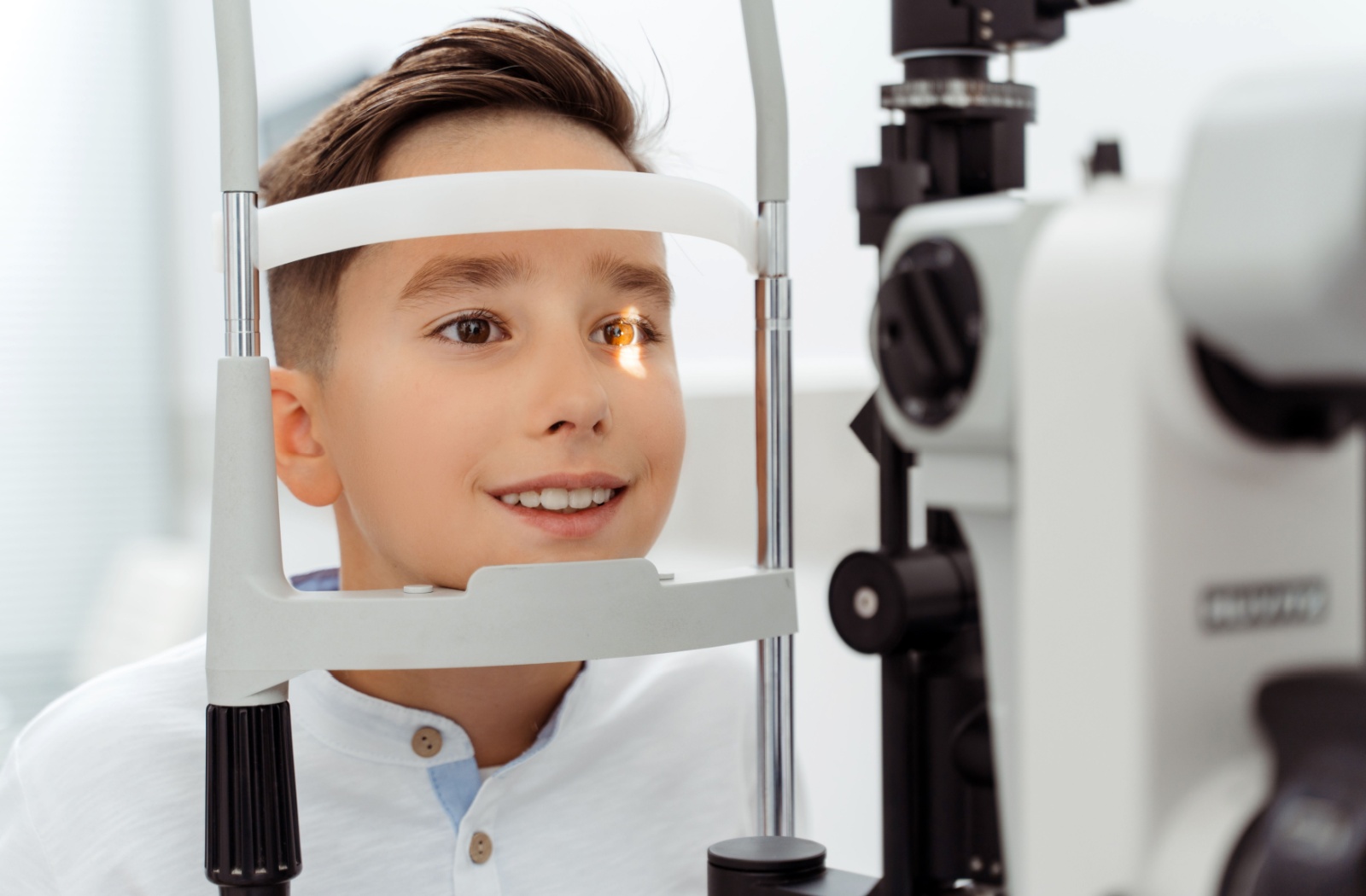 Boy smiling during an eye exam at the optometrist office.