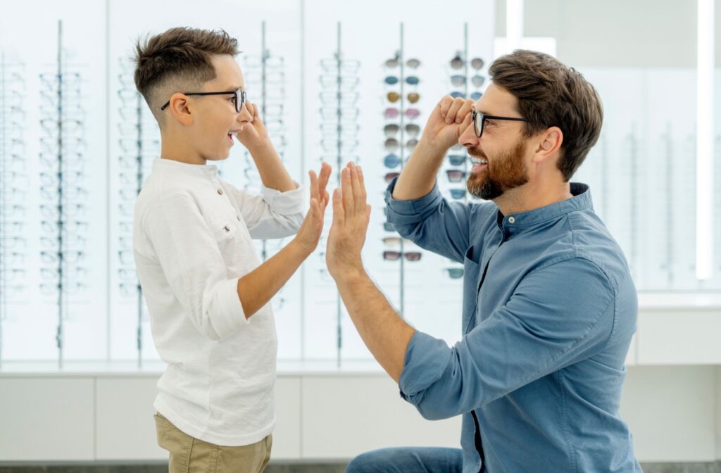 Child and father trying on glasses after an eye exam at the optometrist.