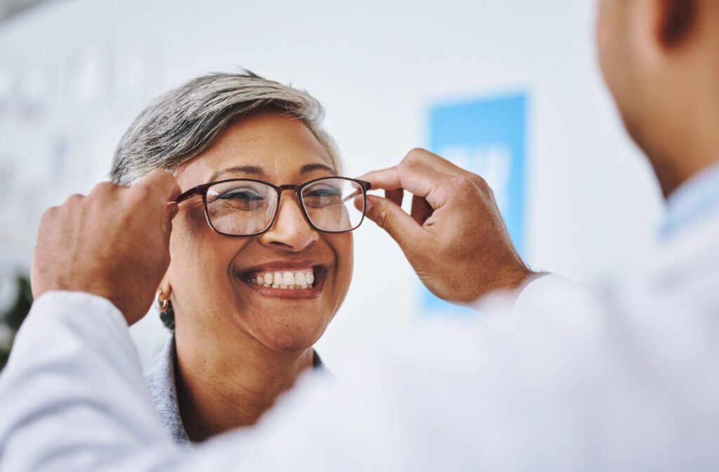 Optometrist putting glasses on a smiling patient