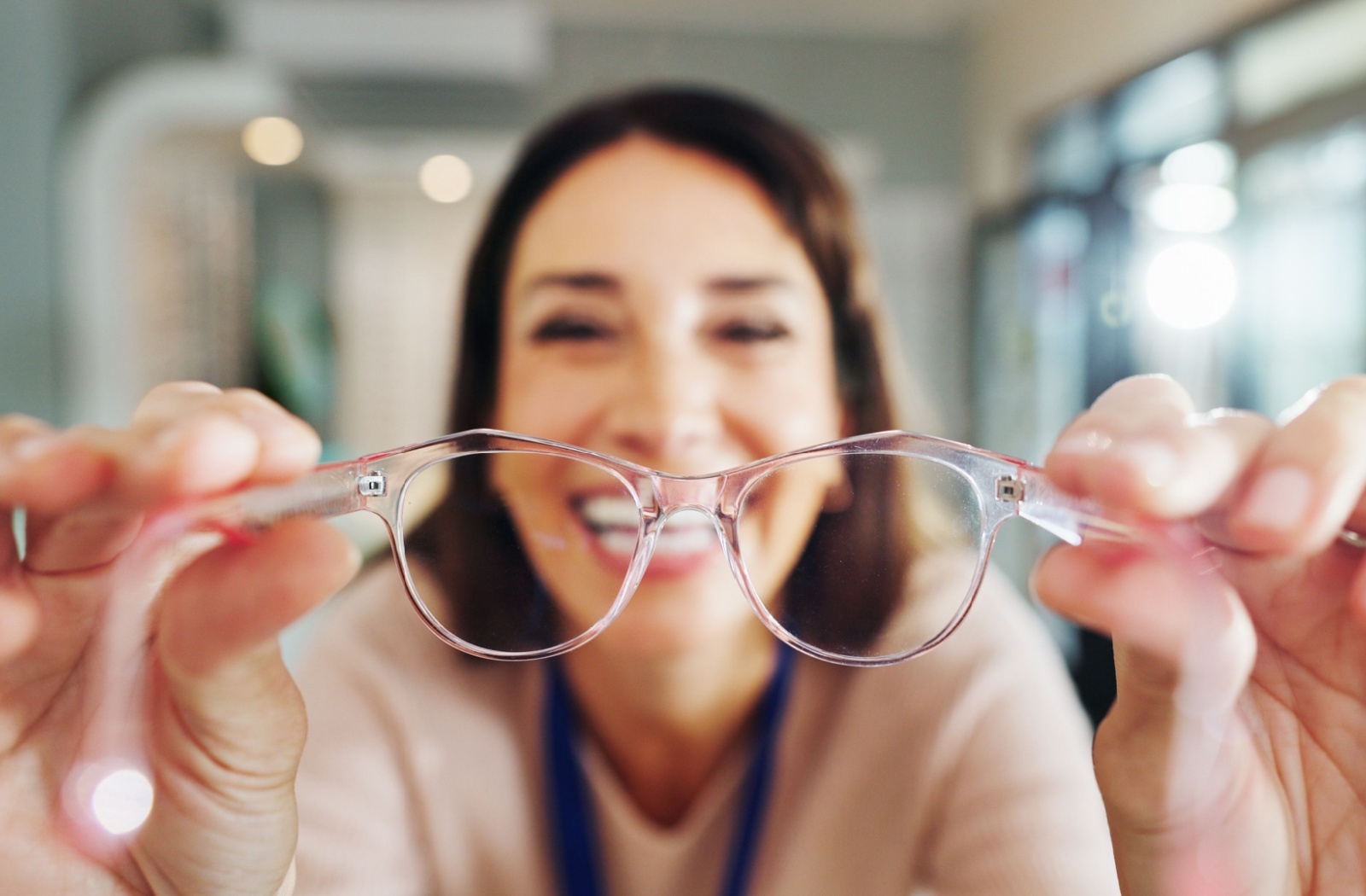 A slightly fuzzy image of a women holding up a pair of clear glasses