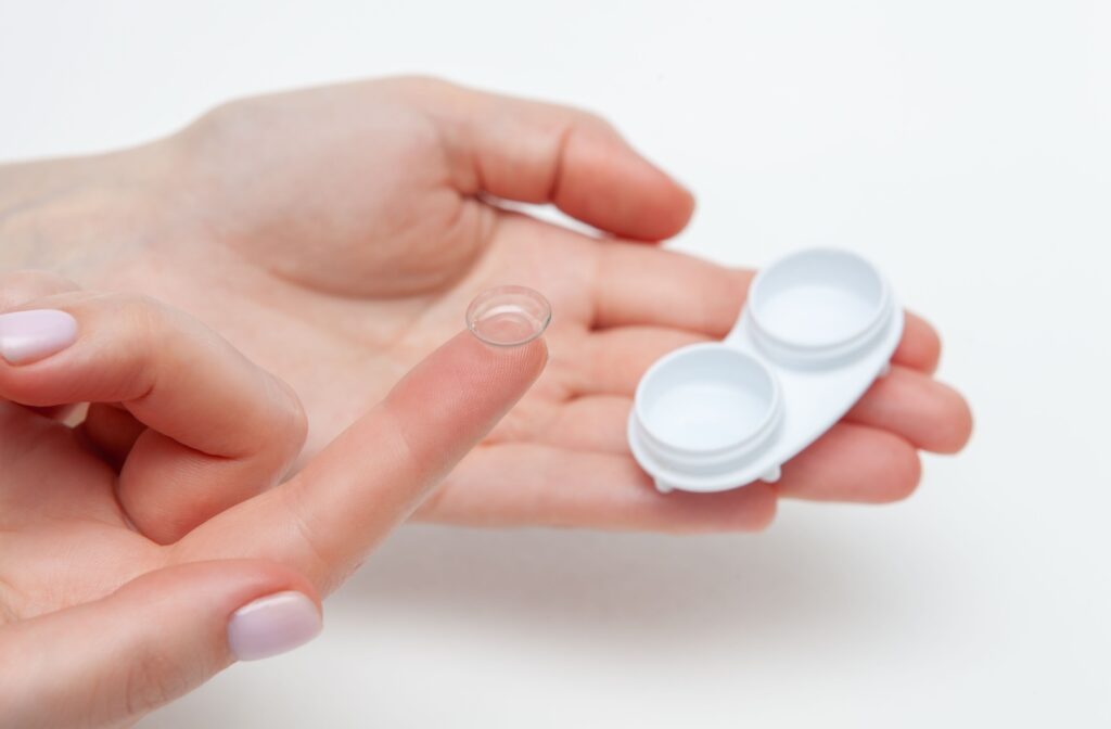 Close up of a hand holding a contact lens case and a contact lens