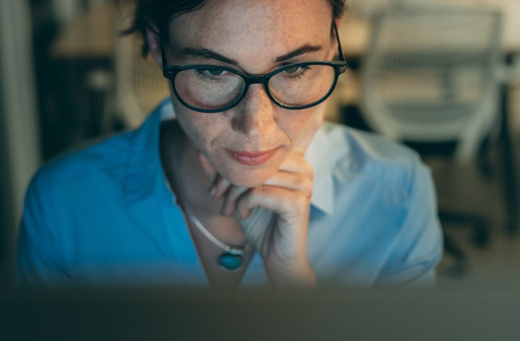 A person wearing glasses while they look at their computer screen