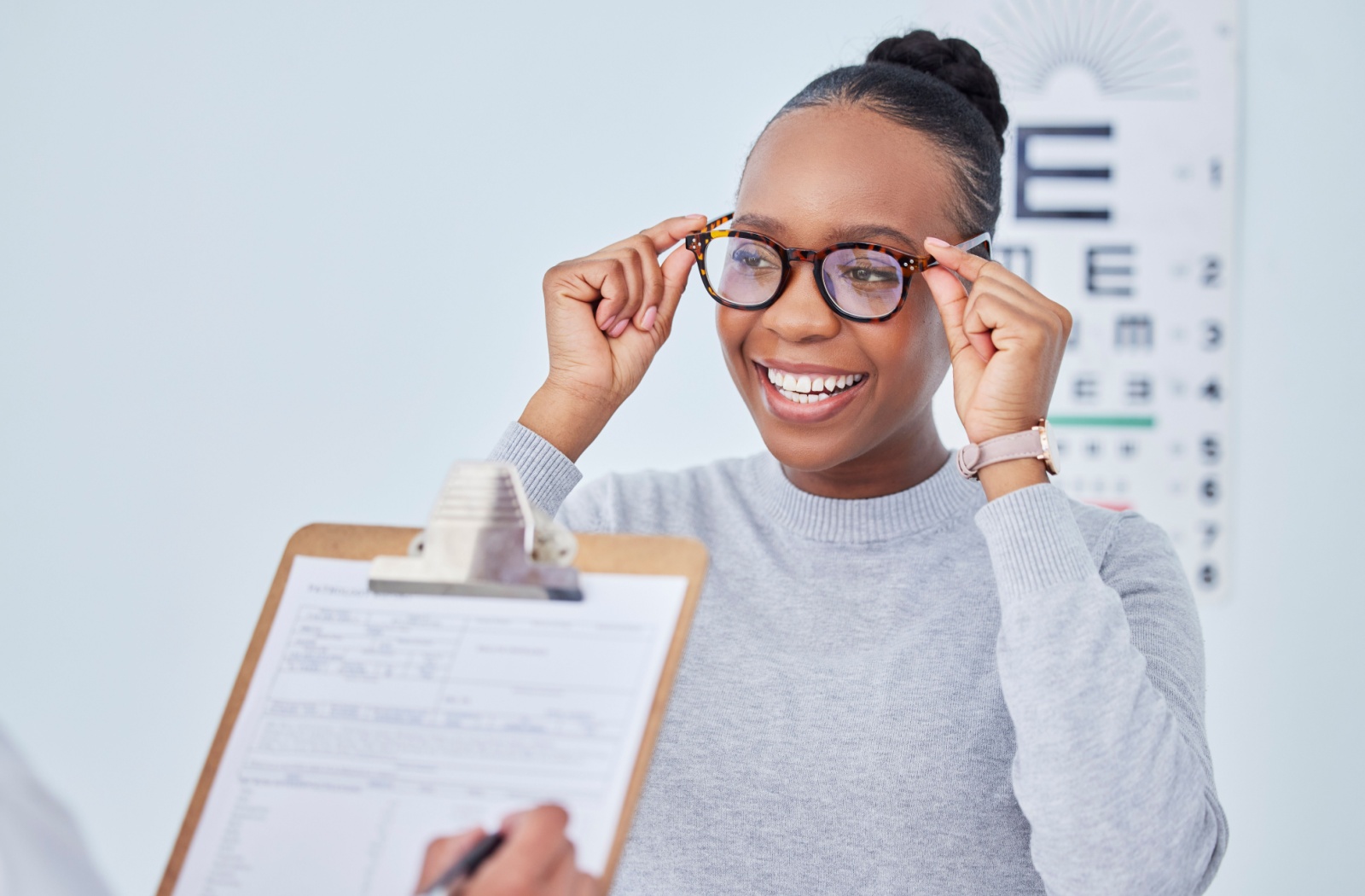 A person smiling while wearing a pair of glasses at the optometrist